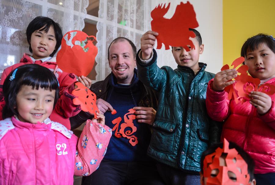 Kevin and the kids show their paper cut works Jan. 20. (Photo/Xinhua)
