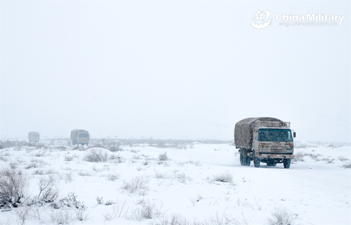 Military trucks maneuver in snowfield