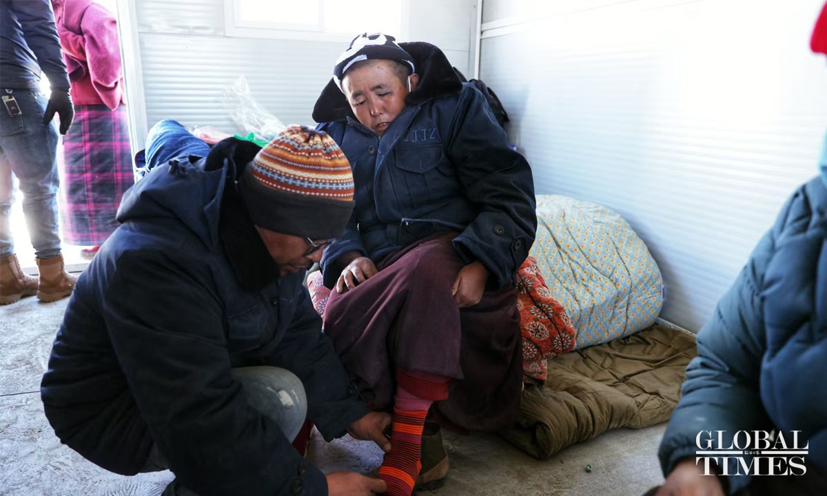 Staff members from the management committee of Shekar Chode Monastery distribute new thick cotton socks and cotton shoes to monks and nuns at the resettlement site. Photo: Cui Meng/GT