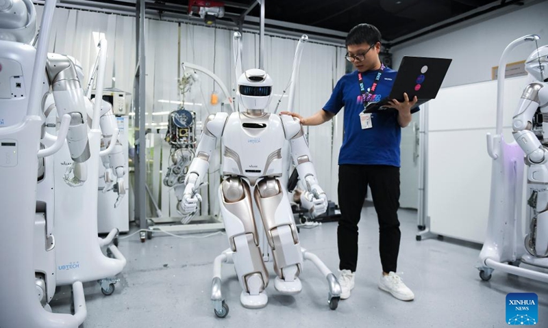 A staff member conducts tests on a Walker X humanoid robot at a sci-tech company in Shenzhen, south China's Guangdong Province, June 26, 2024. The Guangdong-Hong Kong-Macao Greater Bay Area, with its outstanding capabilities in research and development and solid foundation for manufacturing, serves as a fertile ground for the development of humanoid robot sector. (Photo: Xinhua)