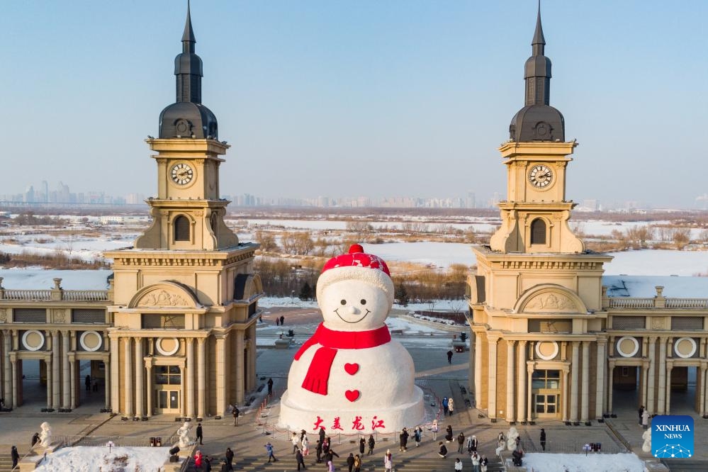 A drone photo taken on Jan. 5, 2024 shows tourists having fun in front of a giant snowman near the Songhua River in Harbin, northeast China's Heilongjiang Province. Known as China's 