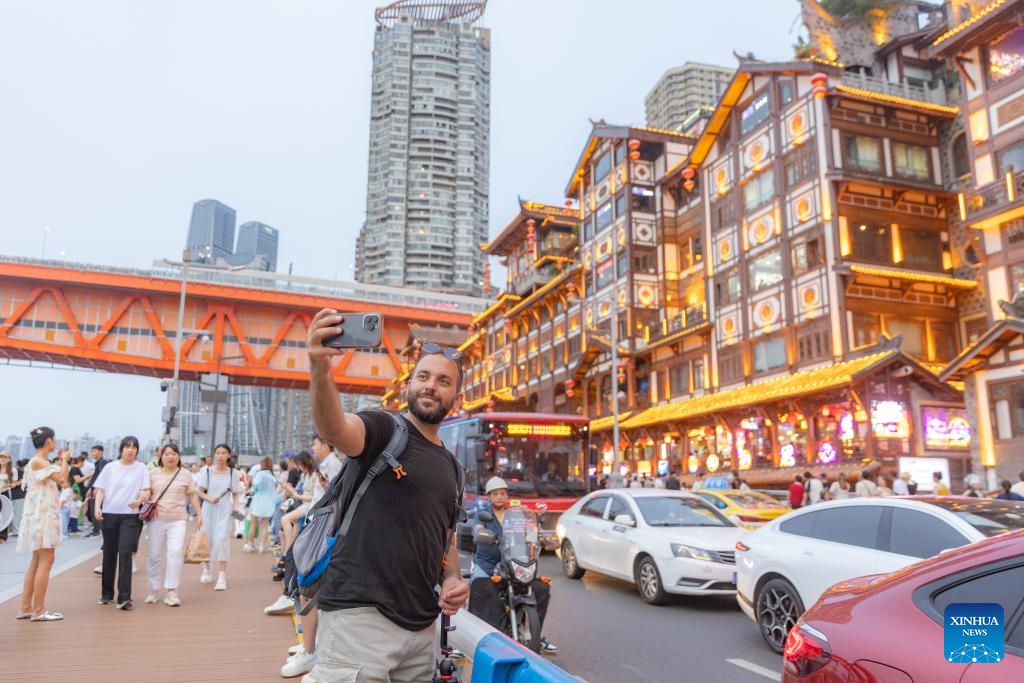 A tourist from Pakistan take a selfie at Hongyadong scenic area in Yuzhong district, in southwest China's Chongqing, July 8, 2024. Chongqing has handled more than 150,000 inbound and outbound foreign passengers in the first half of this year, 4.9 times that of the same period last year. With optimized visa policies, Chongqing keeps on improving the itinerary management for inbound tour groups, offering foreign travelers more flexible choices on the ports of entry and exit. (Photo: Xinhua)